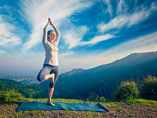 Image showing Woman doing yoga asana Vrikshasana tree pose in mountains outdoors
