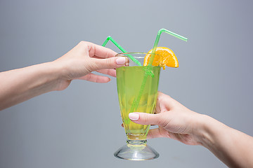 Image showing The female hands with cocktail on gray background
