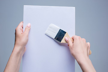 Image showing Hands holding painting brush on white canvas