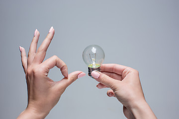 Image showing Hand holding an incandescent light bulb on gray background