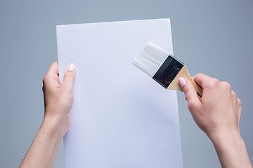 Image showing Hands holding painting brush on white canvas