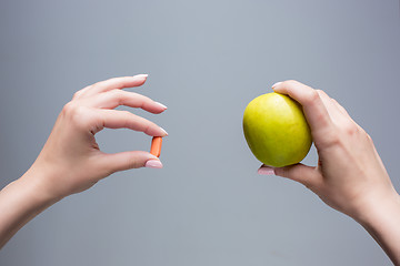 Image showing The female hands with apple and pills 
