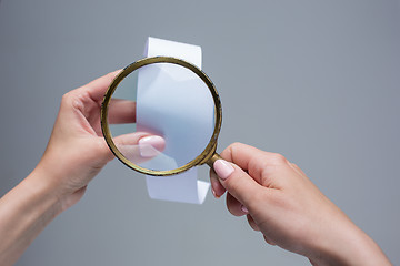 Image showing The female hands with  empty transaction paper or paper check and magnifier