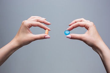 Image showing The female hands with sweet candy and pills 