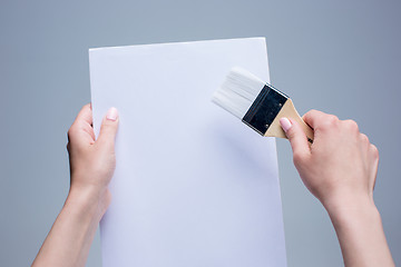 Image showing Hands holding painting brush on white canvas