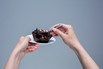 Image showing Female hands keeping cake with spoon on gray