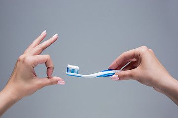 Image showing Toothbrush in woman\'s hands on gray