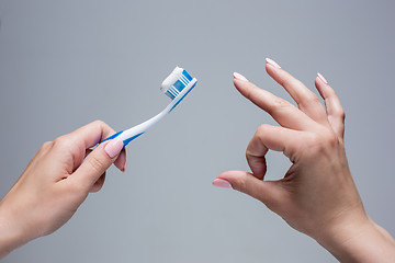 Image showing Toothbrush in woman\'s hands on gray