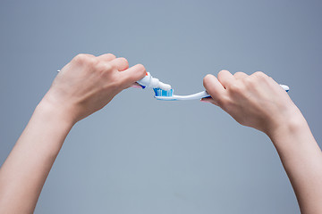 Image showing Toothbrush in woman\'s hands on gray