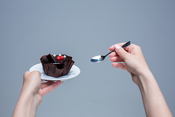 Image showing Female hands keeping cake with spoon on gray