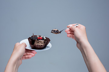 Image showing Female hands keeping cake with spoon on gray