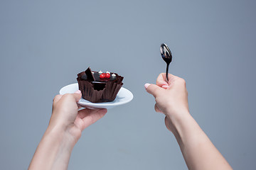 Image showing Female hands keeping cake with spoon on gray