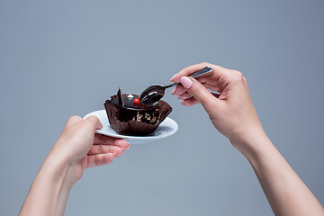 Image showing Female hands keeping cake with spoon on gray