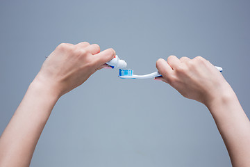 Image showing Toothbrush in woman\'s hands on gray