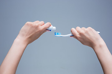 Image showing Toothbrush in woman\'s hands on gray