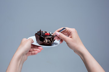 Image showing Female hands keeping cake with spoon on gray