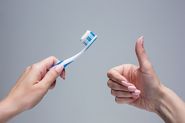 Image showing Toothbrush in woman\'s hands on gray