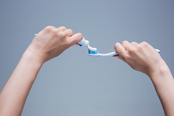 Image showing Toothbrush in woman\'s hands on gray