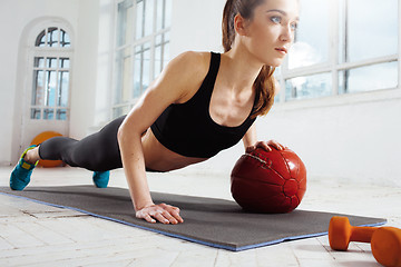 Image showing Beautiful slim brunette doing some gymnastics at the gym