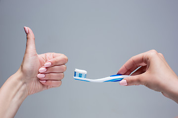 Image showing Toothbrush in woman\'s hands on gray