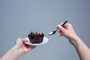 Image showing Female hands keeping cake with spoon on gray