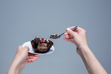 Image showing Female hands keeping cake with spoon on gray