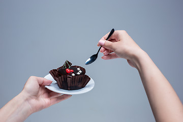 Image showing Female hands keeping cake with spoon on gray