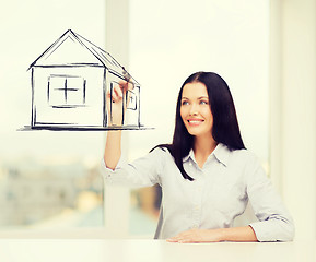 Image showing smiling woman drawing house on virtual screen