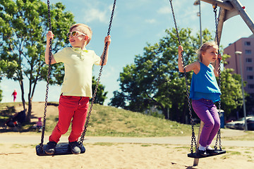 Image showing two happy kids swinging on swing at playground