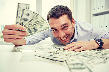 Image showing happy businessman with heap of money in office