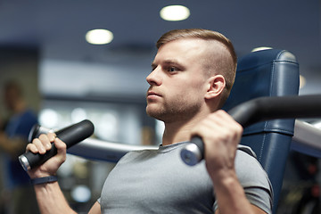 Image showing man exercising and flexing muscles on gym machine