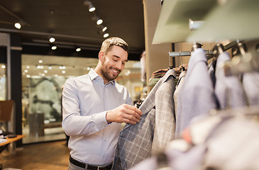 Image showing happy young man choosing clothes in clothing store