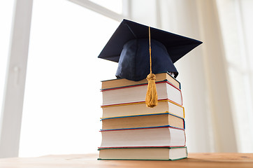 Image showing close up of books and mortarboard on wooden table