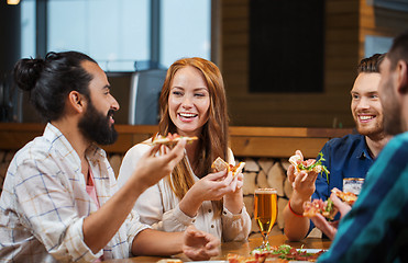 Image showing friends eating pizza with beer at restaurant