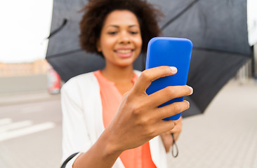 Image showing close up of woman with umbrella and smartphone