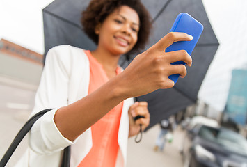 Image showing close up of woman with umbrella and smartphone