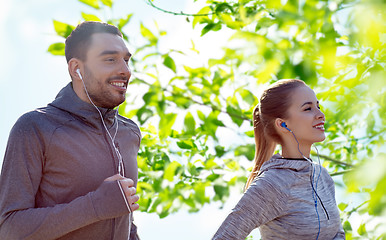 Image showing happy couple with earphones running in city