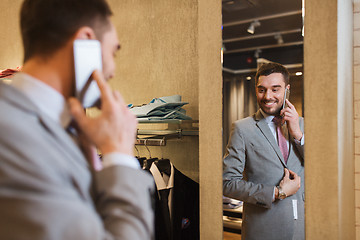 Image showing man calling on smartphone at clothing store mirror