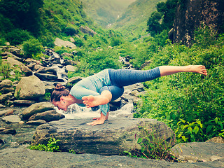 Image showing Young sporty fit woman doing yoga oudoors at tropical waterfall