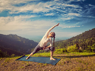 Image showing Woman practices yoga asana Utthita Parsvakonasana outdoors