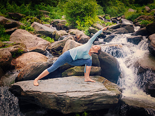 Image showing Woman practices yoga asana Utthita Parsvakonasana outdoors