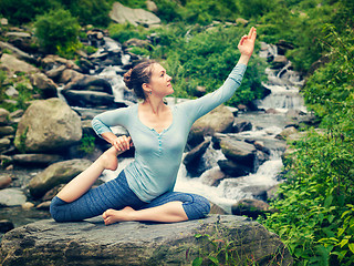 Image showing Sorty fit woman doing yoga asana outdoors at tropical waterfall