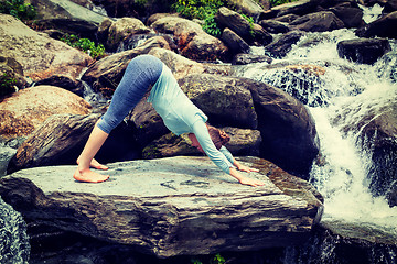 Image showing Young sporty fit woman doing yoga oudoors at tropical waterfall