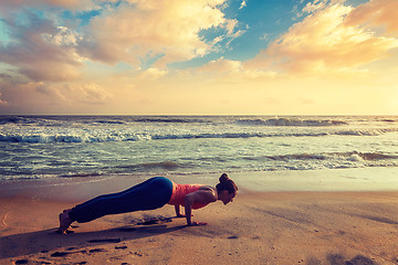 Image showing Woman practices yoga asana Chaturanga Dandasana at the beach