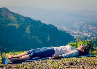 Image showing Woman relaxes in yoga asana Savasana outdoors