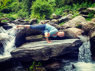 Image showing Young sporty fit woman doing yoga oudoors at tropical waterfall