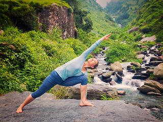 Image showing Woman practices yoga asana Utthita Parsvakonasana outdoors
