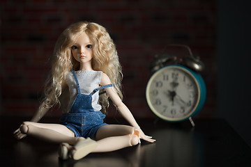 Image showing doll on the background of the old clock.