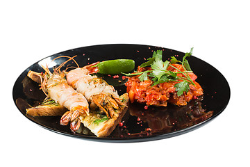 Image showing perfect dish with shrimps on a black plate. seafood. Isolated  white background