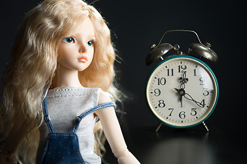 Image showing doll on the background of the old clock.